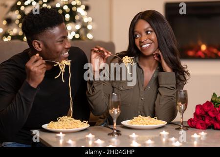 Afrikanische Ehepartner beim Abendessen zum Valentinstag Essen von Pasta Indoor Stockfoto