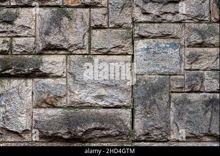 Alte verwitterte Wand aus Granitsteinen, abstrakter Hintergrund. Stockfoto