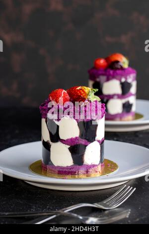 Mini-Kuchen mit Waldfrüchten auf dunklem Hintergrund. Nahaufnahme. Vertikale Ansicht Stockfoto