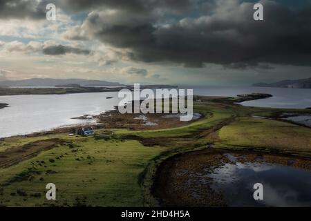 Luftaufnahme der Isle of Skye mit dramatischen Wolken und Wetter, ein Bauernhaus auf einer kleinen Insel, umgeben von Wasser Stockfoto
