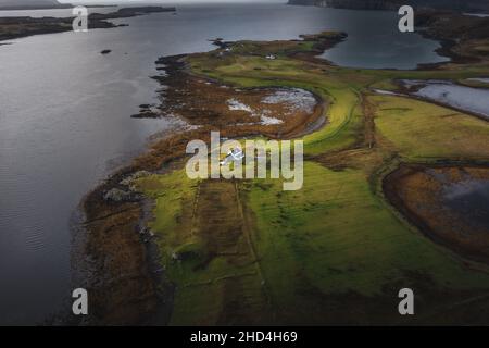 Luftaufnahme der Isle of Skye mit dramatischen Wolken und Wetter, ein Bauernhaus auf einer kleinen Insel, umgeben von Wasser Stockfoto