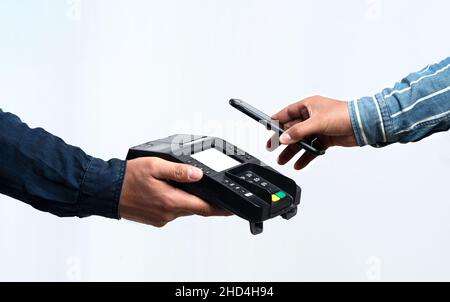 Hände halten POS-Gerät und Smartphone auf isoliertem weißem Hintergrund. Kontaktloses und einfaches Zahlungskonzept. Stockfoto