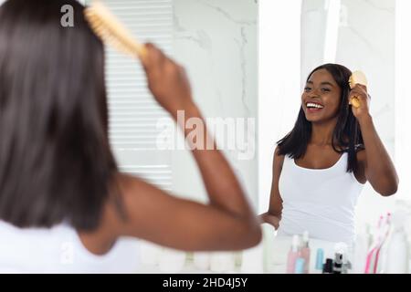 Schöne Afroamerikanische Frau Kämmt Ihr Haar Mit Bambusbürste Im Badezimmer Stockfoto