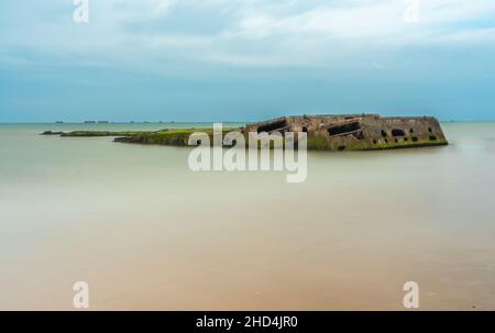 Arromanches, Frankreich - 2. August 2021: Überreste eines künstlichen militärischen Landungshafens in Arromanches in der Normandie - Langzeitbelichtung Stockfoto