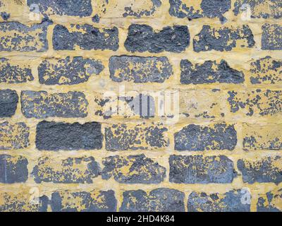 Graue Zinkblockwand mit gelber abblätternder Farbe Stockfoto