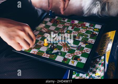 KORONADAL, PH – 25. DEZ 2021:Mädchen spielen Schlangen und Leitern Brettspiel AKA Moksha Patam, Rutschen und Leitern, oder Bibel Höhen und Tiefen von 10x10 Stockfoto