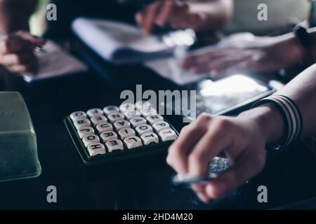 KORONADAL, PH – 25. DEZEMBER 2021: Hände von Spielern auf dem Tisch, die das beliebte Boggle-Spiel aus den 5x5-er Jahren spielen. Selektiver Fokus. Stockfoto