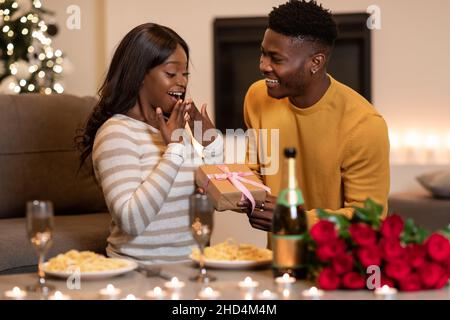 Black Boyfriend Überraschende Freundin Mit Eingewickelten Geschenk Feiern Valentine Indoor Stockfoto