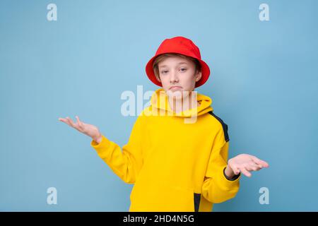 Zeigen Sie mit dem Finger zur Seite. Rapper. Informationsbanner. Stilvoller Hipster-Typ in gelbem Sweatshirt und rotem panama-Hut, der mit dem Finger auf den Kopierraum vor blauem Hintergrund zeigt Stockfoto