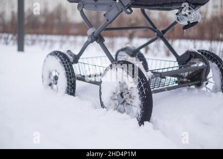 Baby Kinderwagen Rad auf verschneite Straße im Winter. Stockfoto