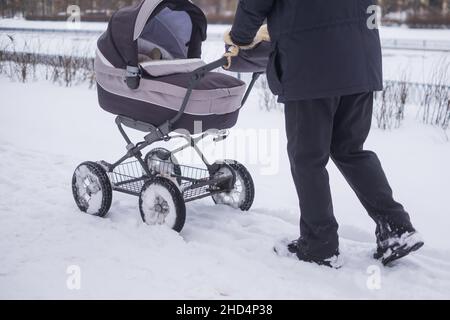 Baby Kinderwagen Rad auf verschneite Straße im Winter. Stockfoto