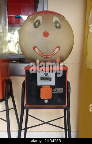 Alte Gummiballmaschine mit glücklichen Gesicht, die elastische Spielzeugbälle ausgibt. Stockfoto