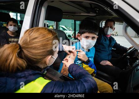 Stuttgart, Deutschland. 03rd Januar 2022. Ein Malteser-Mitarbeiter impft in einer Halle der Messe Stuttgart ein Kind gegen den Corona-Virus. Unter dem Motto "Wir impfen DAS LAND - Teil II" findet vom 03. Bis 06. Januar 2022 in der Messe Stuttgart eine Drive-in-Impfkampagne statt, bei der Interessierte, darunter auch Kinder, von 7 bis 11 Uhr in der Messehalle 9 geimpft werden können. Quelle: Christoph Schmidt/dpa/Alamy Live News Stockfoto