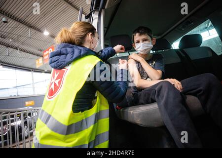 Stuttgart, Deutschland. 03rd Januar 2022. Ein Malteser-Mitarbeiter impft in einer Halle der Messe Stuttgart ein Kind gegen den Corona-Virus. Unter dem Motto "Wir impfen DAS LAND - Teil II" findet vom 03. Bis 06. Januar 2022 in der Messe Stuttgart eine Drive-in-Impfkampagne statt, bei der Interessierte, darunter auch Kinder, von 7 bis 11 Uhr in der Messehalle 9 geimpft werden können. Quelle: Christoph Schmidt/dpa/Alamy Live News Stockfoto