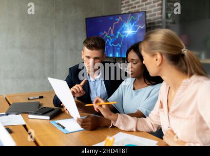 Portrait Von Multiethnischen Kollegen, Die Während Eines Meetings In Modern Office Über Finanzberichte Diskutieren Stockfoto