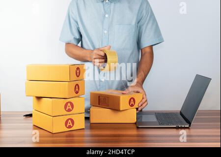Mann, der Klebeband zum Verpacken von Verpackungen für den Verkauf von Online-Geschäften verwendet, Stockfoto