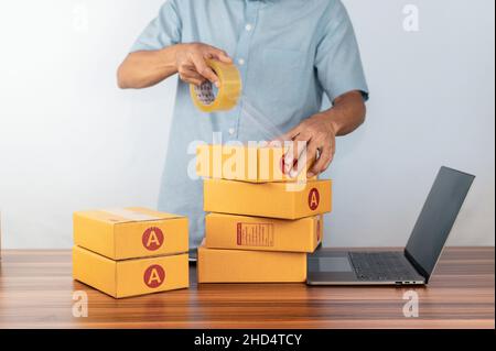 Mann, der Klebeband zum Verpacken von Verpackungen für den Verkauf von Online-Geschäften verwendet, Stockfoto