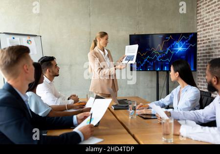 Firmenmeeting. Junge Geschäftsfrau Hält Rede Während Der Konferenz Mit Mitarbeitern Im Büro Stockfoto