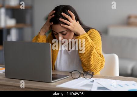 Stressiger Job, Burnout-Konzept. Gestresste arabische Dame, die am Laptop arbeitete und den Kopf berührte und Probleme am Arbeitsplatz hatte Stockfoto