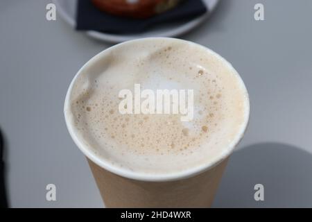 Einen schaumigen Latte in einer Tasse zum Mitnehmen Stockfoto