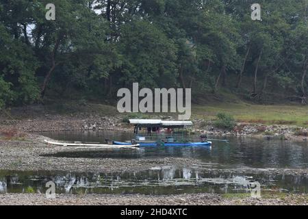 Traditionelles Bambusboot auf dem Fluss Li in Yangshuo China, mit Trocknung der Kleidung. Grüne Bäume im Hintergrund. Das Boot ist blau. Stockfoto
