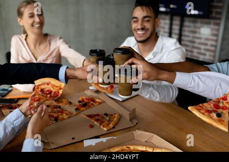 Mittagspause. Kollegen Klirren Take-Away-Kaffeetassen Und Essen Pizza Im Büro Stockfoto