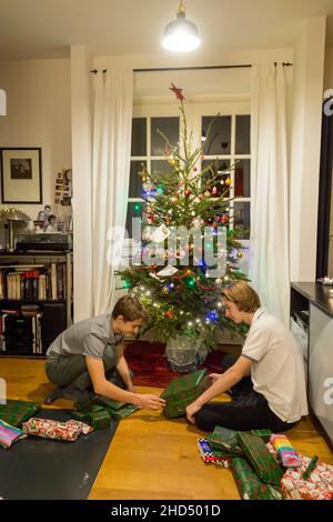Zwei Brüder zu Hause vor dem Weihnachtsbaum öffnen Weihnachtsgeschenke Stockfoto