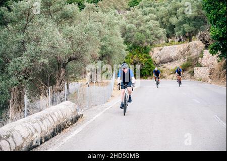 Seniorradler mit zwei unkenntlichen Radfahrern im Hintergrund auf einem Bergpass Stockfoto