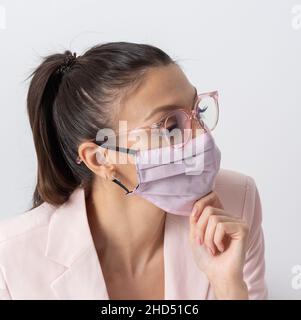 Salisbury, Wiltshire, Großbritannien. 2021. Attraktive Frau mit Pferdeschwanz und Brille in rosa Gesichtsmask während des Covid. Stockfoto