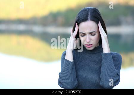 Vorderansicht Porträt einer Frau, die an Migräne in einem See leidet Stockfoto