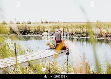 Die schwarze Frau sitzt auf dem Dock und blickt zur Seite Stockfoto