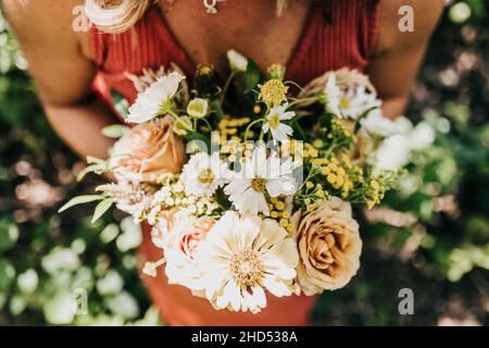 Nahaufnahme einer Frau mit einem Strauß frischer Blumen über dem Kopf Stockfoto
