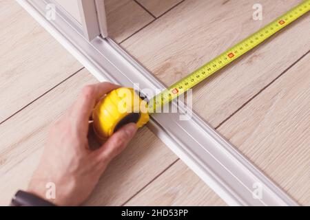 Maßband für die Tiefe des Kleiderschranks mit Schiebetüren von der Wand bis zu den Ablageschienen Stockfoto