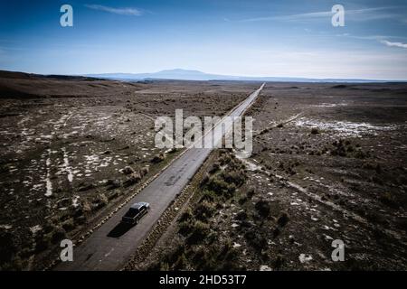 Luftaufnahme Einzelfahrzeug auf langer gerader Straße in Wüstenlandschaft Stockfoto
