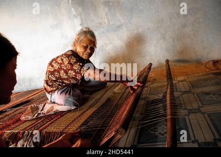 Alte Frau, die in Duy Vinh Village, Vietnam, eine traditionelle Segge webt Stockfoto