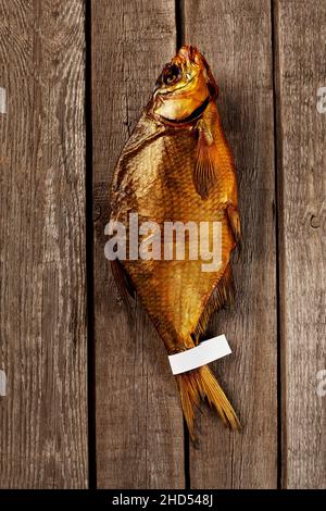 Ganze geräucherte Brasse mit Etikett am Schwanz auf rauhen Holzbrettern Bac Stockfoto