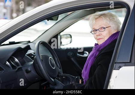 Stilvolle ältere Frau, die in ihrem Auto sitzt. Stockfoto