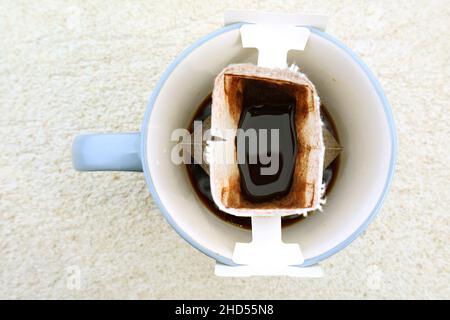 Draufsicht auf eine Tasse aromatischen tragbaren Tropfkaffees, der auf einem Steintisch zubereitet wird Stockfoto