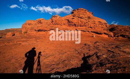 Silhouette eines Fotografen, der in der roten Felsenwüste von Utah fotografiert. Das Bild schildert die Landschaft und den Grund, dort zu sein. Stockfoto