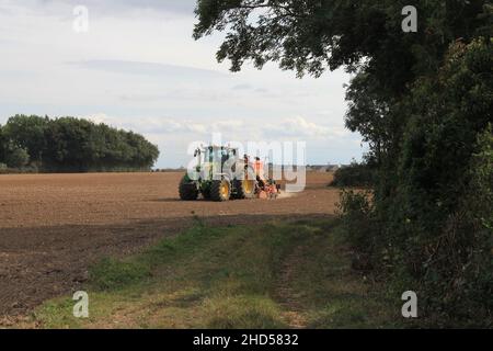 Garforth in der Nähe von Leeds West Yorkshire, Großbritannien 18th. Juli 2021 Bauer pflügt und sät ein Feld mit Traktor und Sämaschine an einem Sommermorgen Stockfoto