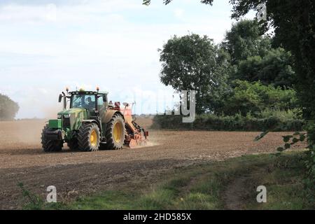 Garforth in der Nähe von Leeds West Yorkshire, Großbritannien 18th. Juli 2021 Bauer pflügt und sät ein Feld mit Traktor und Sämaschine an einem Sommermorgen Stockfoto