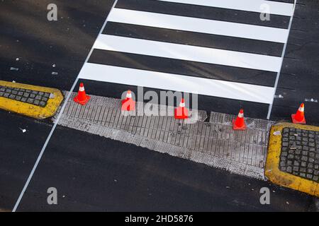 Frisch gestrichene Zebrastreifen auf einer Stadtstraße mit Kegeln und Klebeband auf dem Asphalt Stockfoto