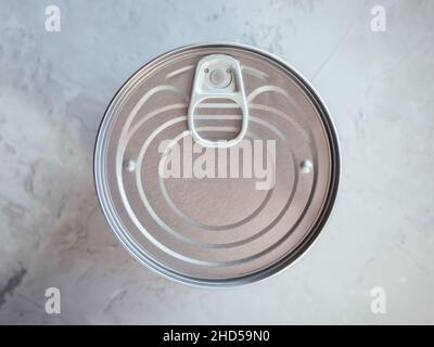 Konserven in Zinndose auf betongrauem Hintergrund. Nicht verderbliche, langlebige Lebensmittel, die unter Notfallbedingungen überleben können. Nahrungsmittelkrise Stockfoto