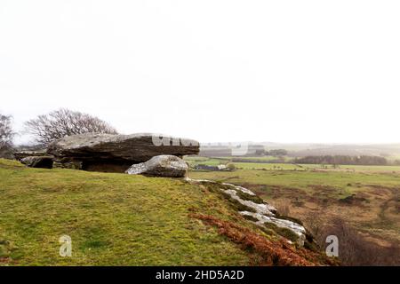 Rock mit Blick auf die Landschaft bei Shaftoe Crags in Northumberland, England. Regen fällt auf das Land. Stockfoto