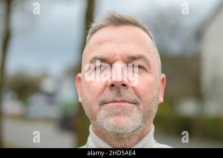 Mann mittleren Alters starrte nachdenklich in einem Nahaufnahme-Headshot mit ernsthaftem Vorsatz auf die Kamera Stockfoto