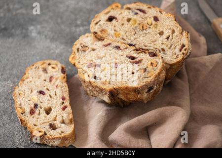 Halbierte Sauerteig-Fruchtbrot mit getrockneten Aprikosen, Preiselbeeren und Haselnüssen. Stockfoto