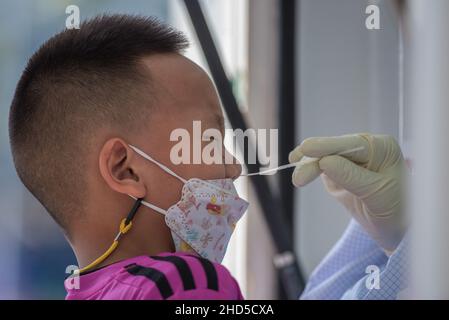 Bangkok, Thailand. 03rd Januar 2022. Ein Gesundheitsmitarbeiter nimmt während der COVID-19-Tests für Reisende am Bahnhof Hua Lamphong in Bangkok eine Nasenabstrichprobe von einem Kind ab.das thailändische Gesundheitsministerium führt an ankommenden Passagieren Massen-COVID-19-Tests durch, die meisten von ihnen kehren zu den Neujahrsfeiern nach Hause zurück. Während das Land seine Bemühungen verstärkt, die Ausbreitung der Coronavirus-Krankheit (COVID-19) zu verhindern, berichtete das thailändische Gesundheitsministerium heute Morgen, dass in Thailand mehr als 1.780 Fälle von Omicron entdeckt wurden. Kredit: SOPA Images Limited/Alamy Live Nachrichten Stockfoto