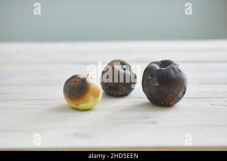 Hässlich Obst. Drei faulen Äpfeln auf dem hölzernen Tisch Stockfoto