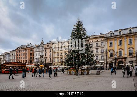 Krakau, Polen-Dezember 17,2021. Berühmter Weihnachtsmarkt auf dem Hauptplatz, Rynek Glowny, geschmückter Weihnachtsbaum, Holzhütten, Menschen, die eine festliche Atmosphäre genießen. Stockfoto