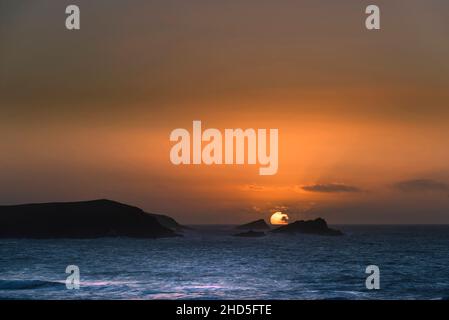 Ein intensiver spektakulärer Sonnenuntergang über der Fistral Bay in Newquay in Cornwall. Stockfoto